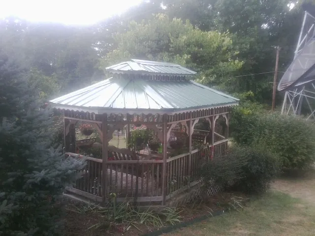 Green metal roof on a backyard gazebo surrounded by garden beds in Victoria