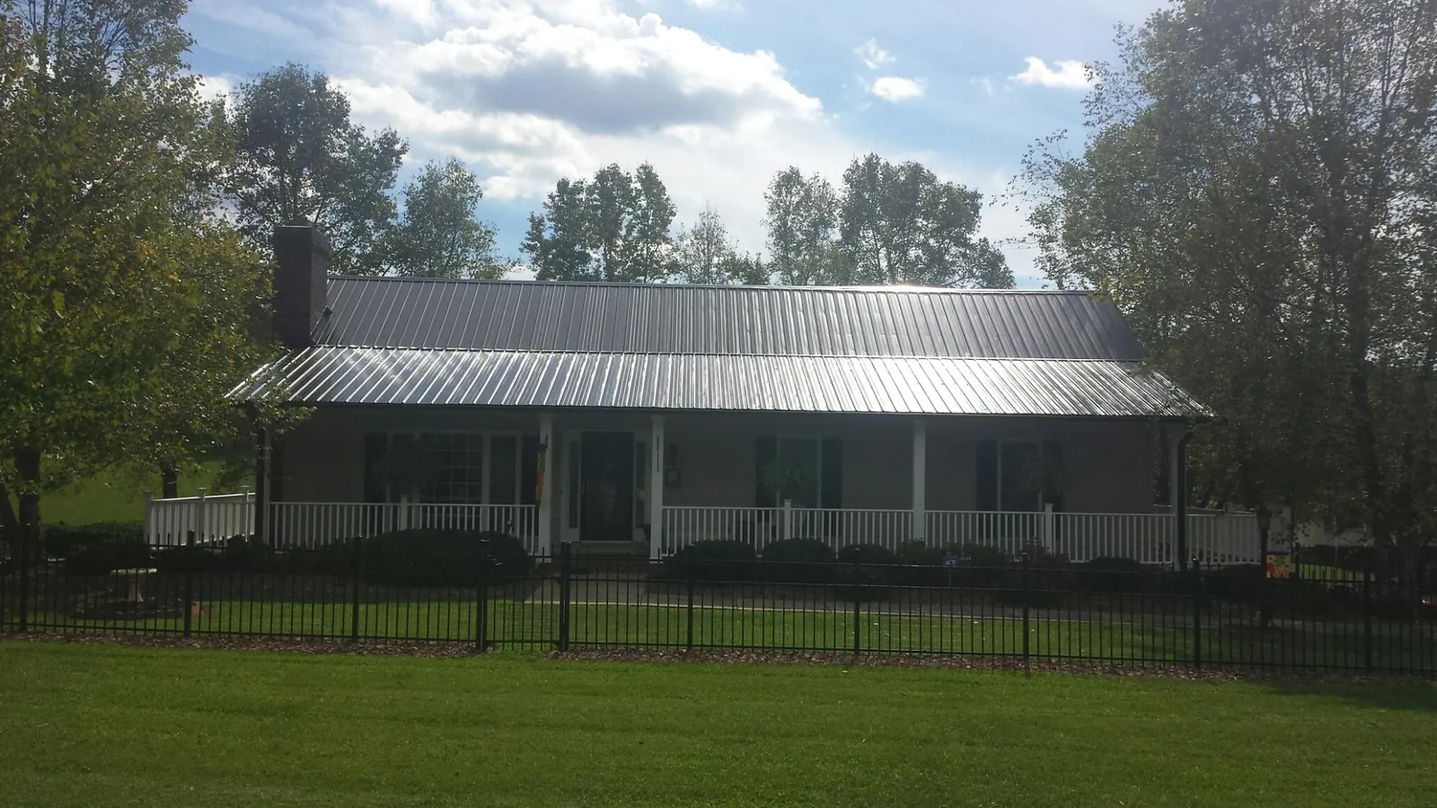 Gray metal roof on a brick ranch with a full width front porch — Gutter Guard Installation work by our crew in Victoria