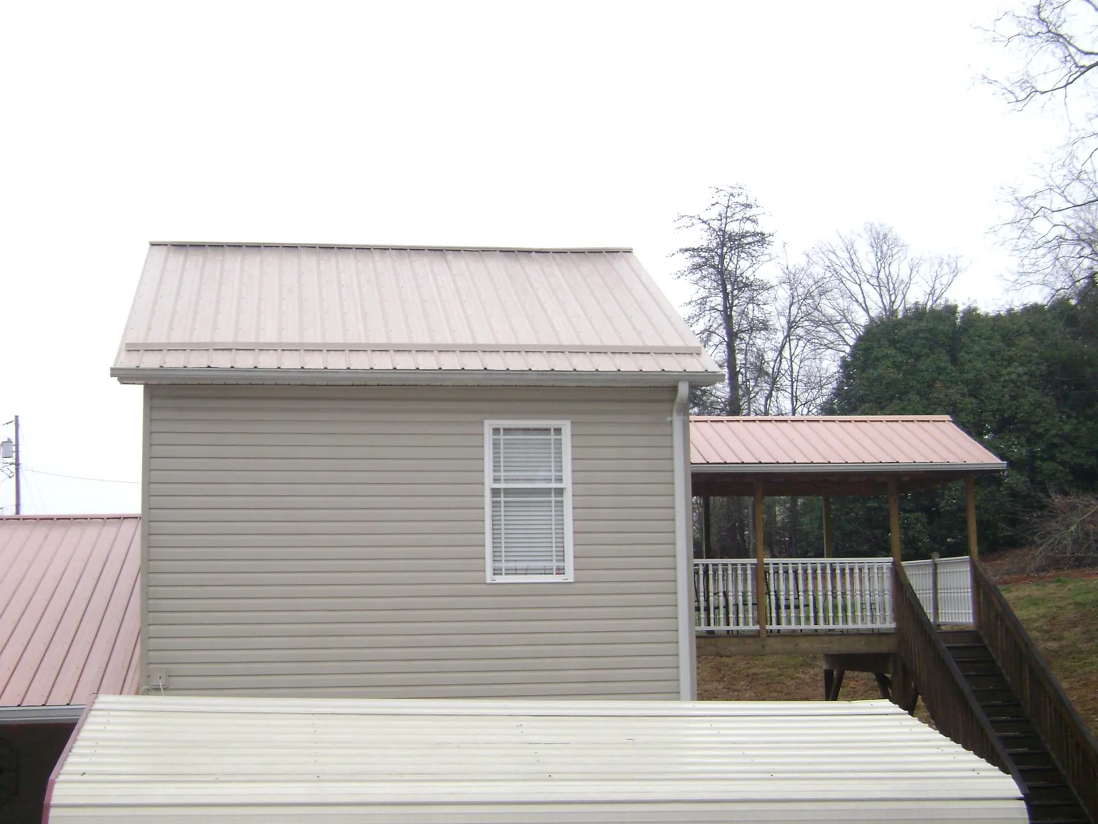 Tan metal roofs on a two story addition and attached porch, from a Roof Replacement job in Victoria